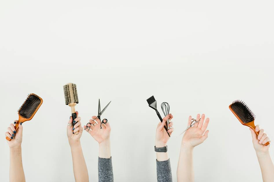 Collection of hair styling tools including curling irons and straighteners on a sleek vanity table