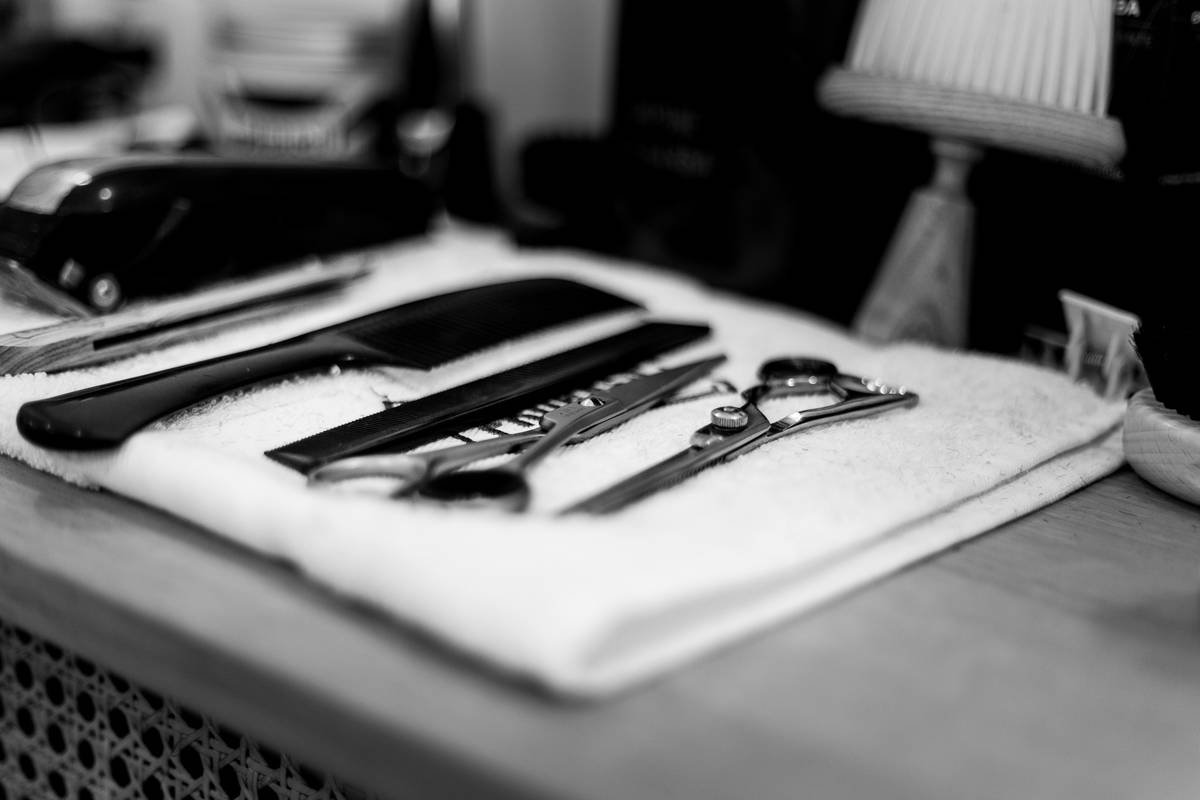 Professional salon hair styling kit laid out on marble counter with heat protectant spray and sectioning clips